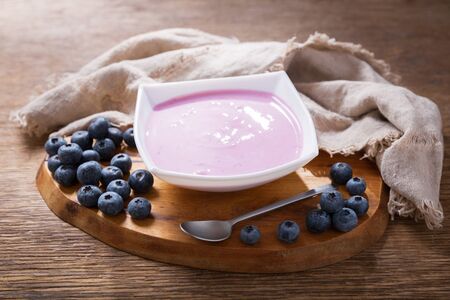 bowl of blueberry yogurt with fresh berries on a wooden tableの写真素材