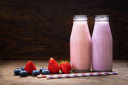bottles of smoothies with fresh berries on a wooden tableの写真素材