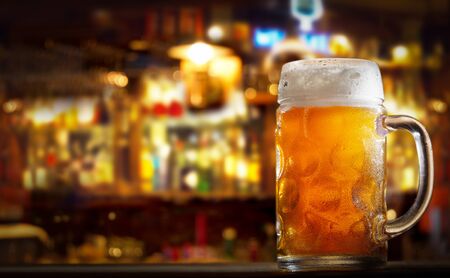 close up of cold mug of beer in a bar on a wooden tableの写真素材