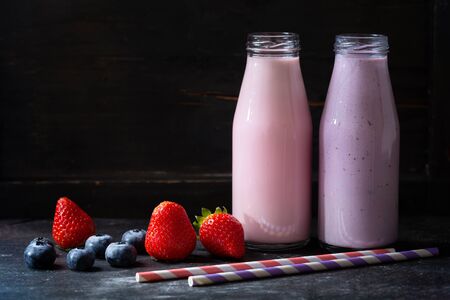 two bottles of smoothies with fresh berriesの写真素材