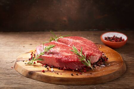fresh meat with rosemary and spices on a wooden boardの写真素材