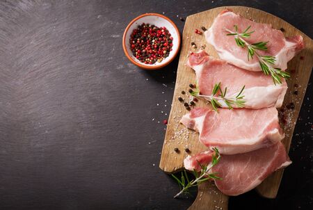 fresh pork chops with rosemary and spices on wooden board, top viewの写真素材