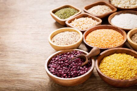 A bowls of legumes, lentils, chickpeas, rice and beans on wooden tableの写真素材