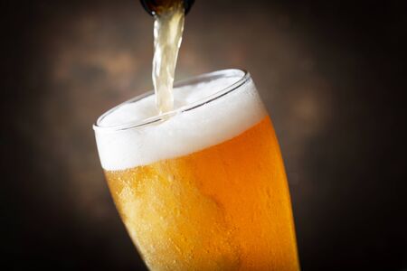 beer pouring into glass on dark backgroundの写真素材