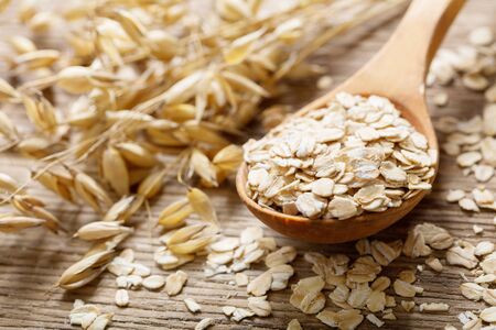 oatmeal flakes and ears of oats on wooden tableの写真素材