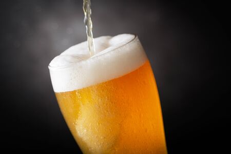 Beer pouring into glass on darkの写真素材