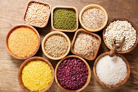 Bowls of legumes, lentils, chickpeas, rice and beans on wooden tableの写真素材