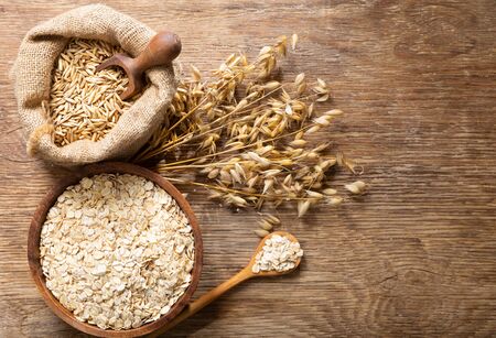 Oatmeal flakes, grains and ears of oats on wooden table, top viewの写真素材