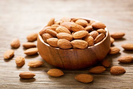 A bowl of almonds on a wooden tableの写真素材