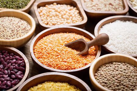 Bowls of legumes, lentils, chickpeas, rice and beans on wooden tableの写真素材