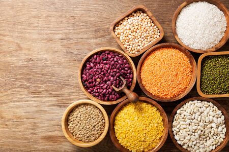 Bowls of legumes, lentils, chickpeas, rice and beans on wooden tableの写真素材