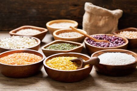 Bowls of legumes, lentils, chickpeas, rice and beans on wooden tableの写真素材