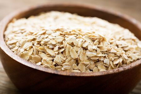 A bowl of oatmeal flakes on wooden tableの写真素材