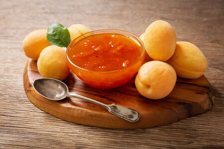 bowl of apricot jam with fresh fruits on a wooden tableの写真素材