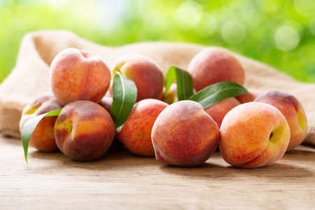 fresh ripe peaches with leaves on a wooden table in a gardenの写真素材