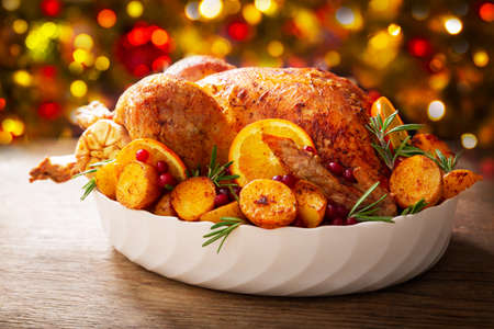 Christmas food. Baked turkey garnished with potato, oranges and cranberries on a wooden tableの写真素材