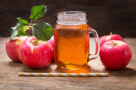 glass jar of apple juice with fresh fruits on a wooden tableの写真素材
