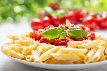 plate of penne pasta with tomato sauce on a wooden tableの写真素材