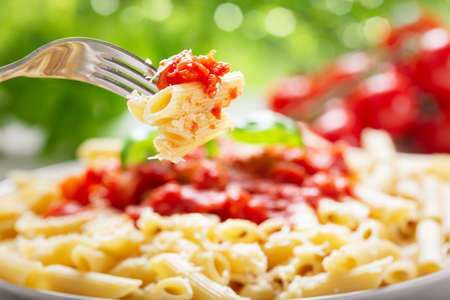Penne pasta with tomato sauce on a fork. Italian food.の写真素材