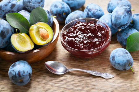 bowl of plum jam and fresh fruits on a wooden tableの写真素材