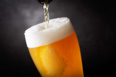 beer pouring into glass on a dark backgroundの写真素材