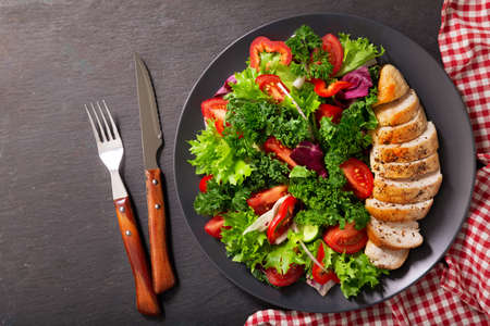 plate of chicken salad with vegetables on dark background, top viewの写真素材