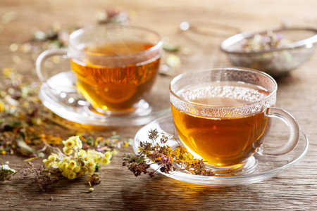Cups of herbal tea with dried herbs on a wooden tableの写真素材