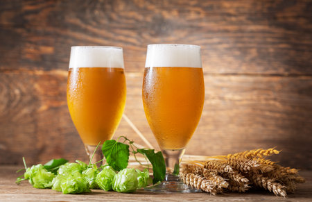 glasses of beer, wheat ears and hops on a wooden backgroundの写真素材