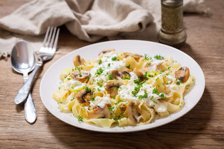 plate of pasta with cream sauce and mushrooms on a wooden tableの写真素材