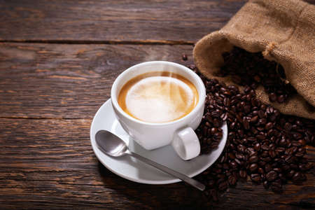 cup of coffee and coffee beans on a rustic wooden tableの写真素材