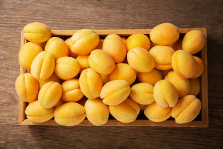 fresh ripe apricots in a box on a wooden table, top viewの写真素材