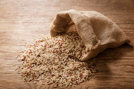 Close up of raw brown rice on a wooden tableの写真素材