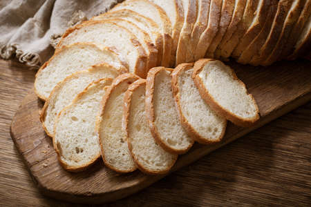 sliced bread on wooden cutting board, top viewの写真素材