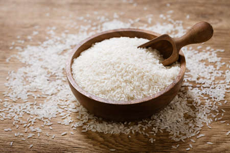 bowl of raw white rice on a wooden boardの写真素材