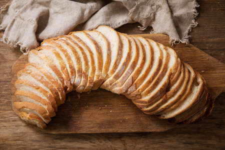 sliced bread on wooden cutting board, top viewの写真素材
