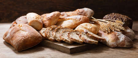 Fresh baked bread and wheat ears on a wooden backgroundの写真素材