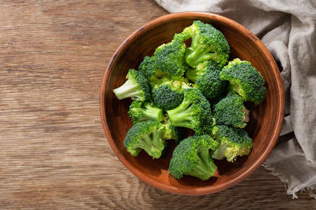 Bowl of fresh broccoli florets on wooden background, top viewの写真素材