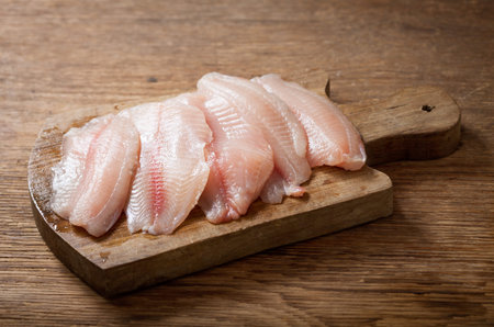 fresh fish fillet of tilapia on a wooden board