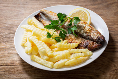 plate of fried fish with french fries on a wooden background