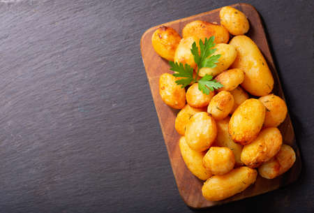 baked potatoes with parsley on a wooden board, top viewの写真素材