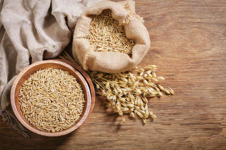 Ears of oat and bowl of grains on wooden background, top viewの写真素材