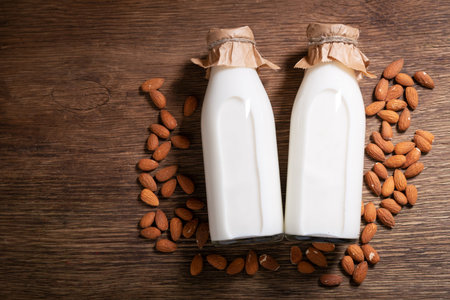 bottles of almond milk with almond on a wooden background, top view