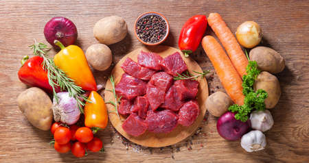 fresh chopped meat with rosemary and ingredients for cooking on wooden background, top viewの写真素材