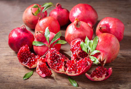 fresh ripe pomegranates with leaves on a wooden tableの写真素材