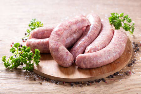 Fresh sausages with spices on a wooden boardの写真素材