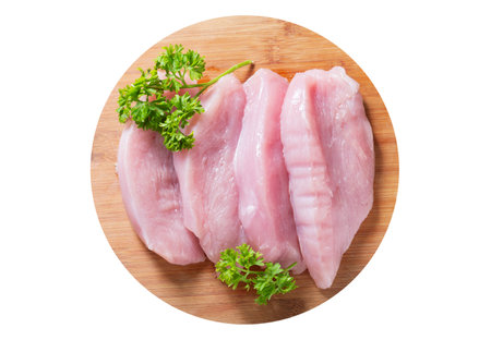 fresh turkey meat with parsley on wooden board isolated on white background, top viewの写真素材