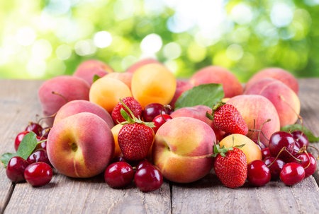close up of fresh fruits on a wooden table on green backgroundの写真素材