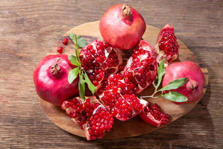 fresh ripe pomegranates with leaves on a wooden table, top viewの写真素材