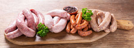 various kind of types of fresh sausages on a wooden boardの写真素材