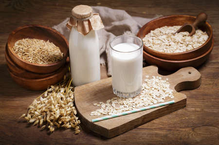 glass of oat milk and oat flakes on wooden tableの写真素材